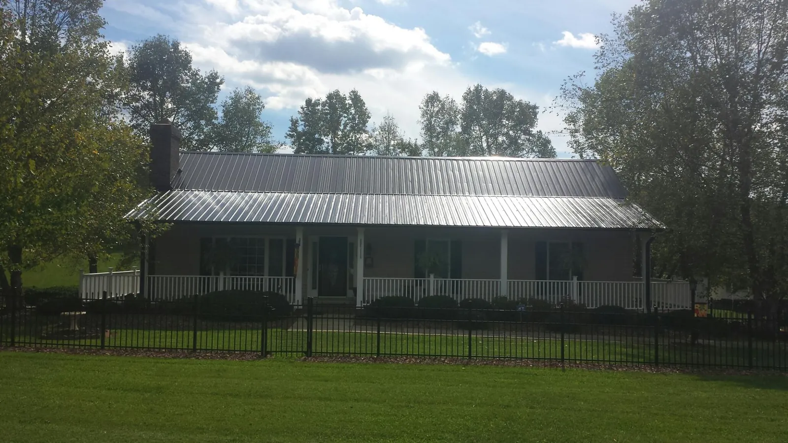 Gray metal roof on a brick ranch with a full width front porch — Gutter Guard Installation work by our crew in Hooper